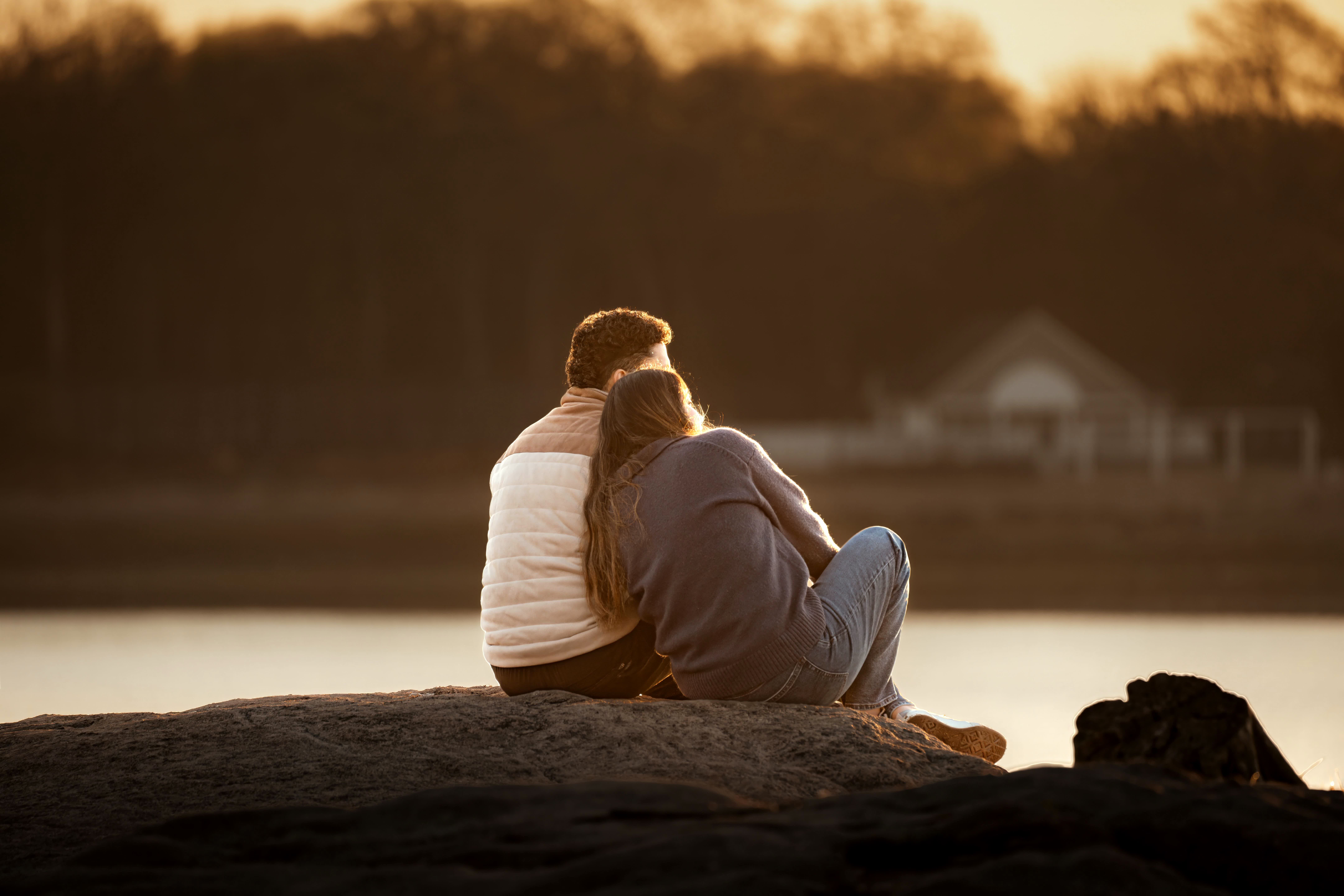 Un couple partage un moment calme au bord de l'eau au coucher du soleil